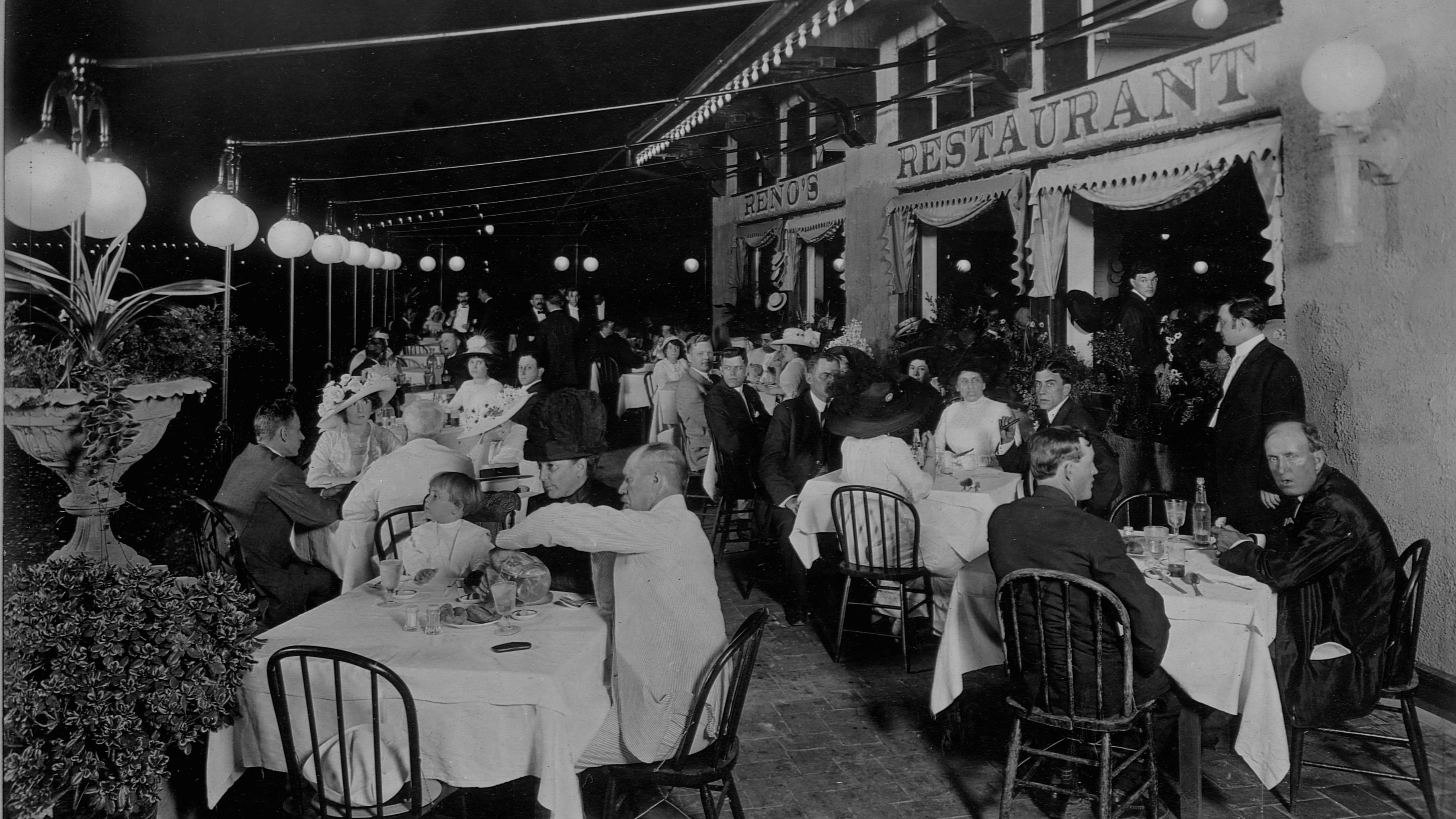 A black-and-white photo of people dining outside