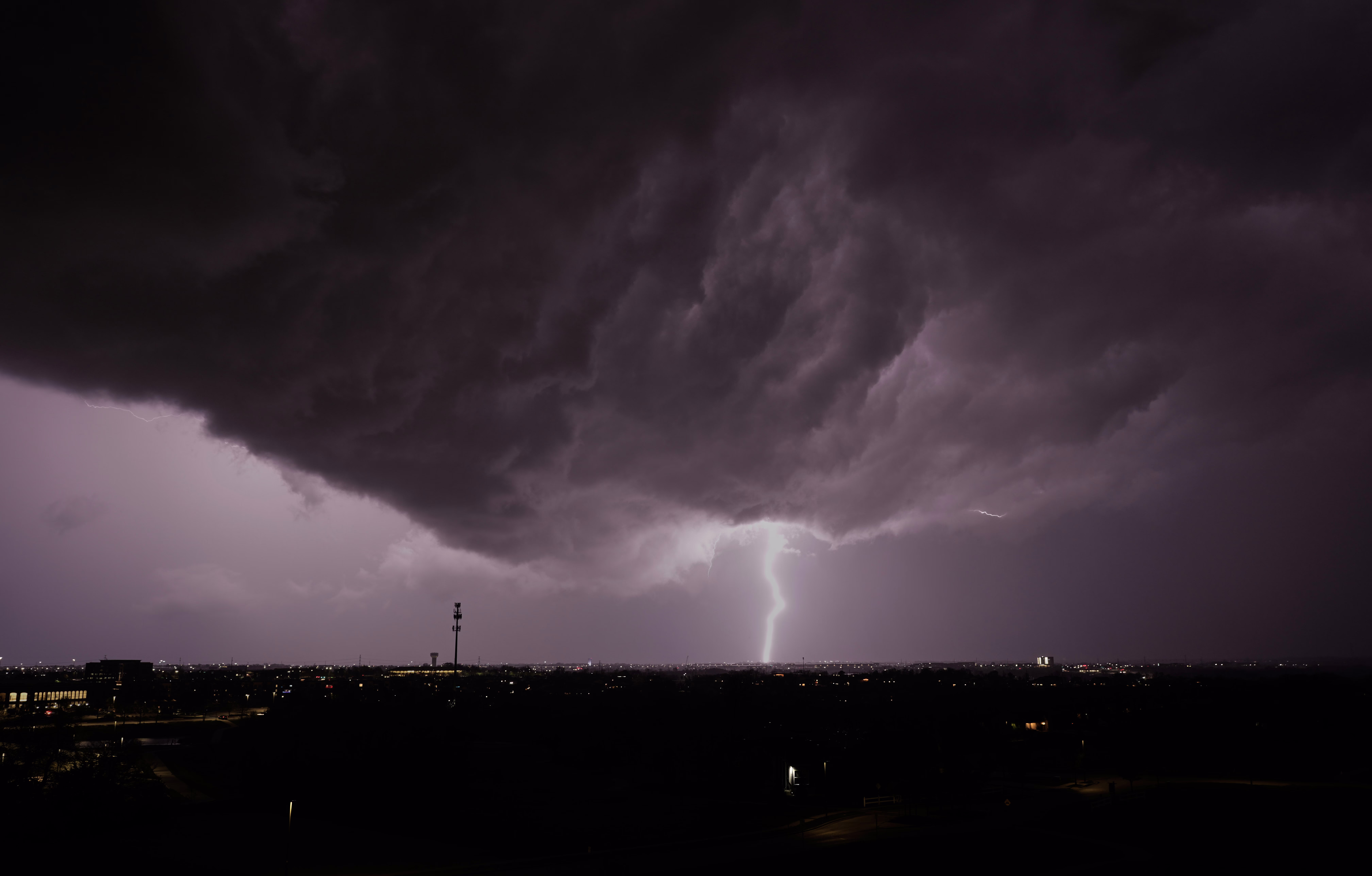 Lightning flashes beneath a dark storm cloud.