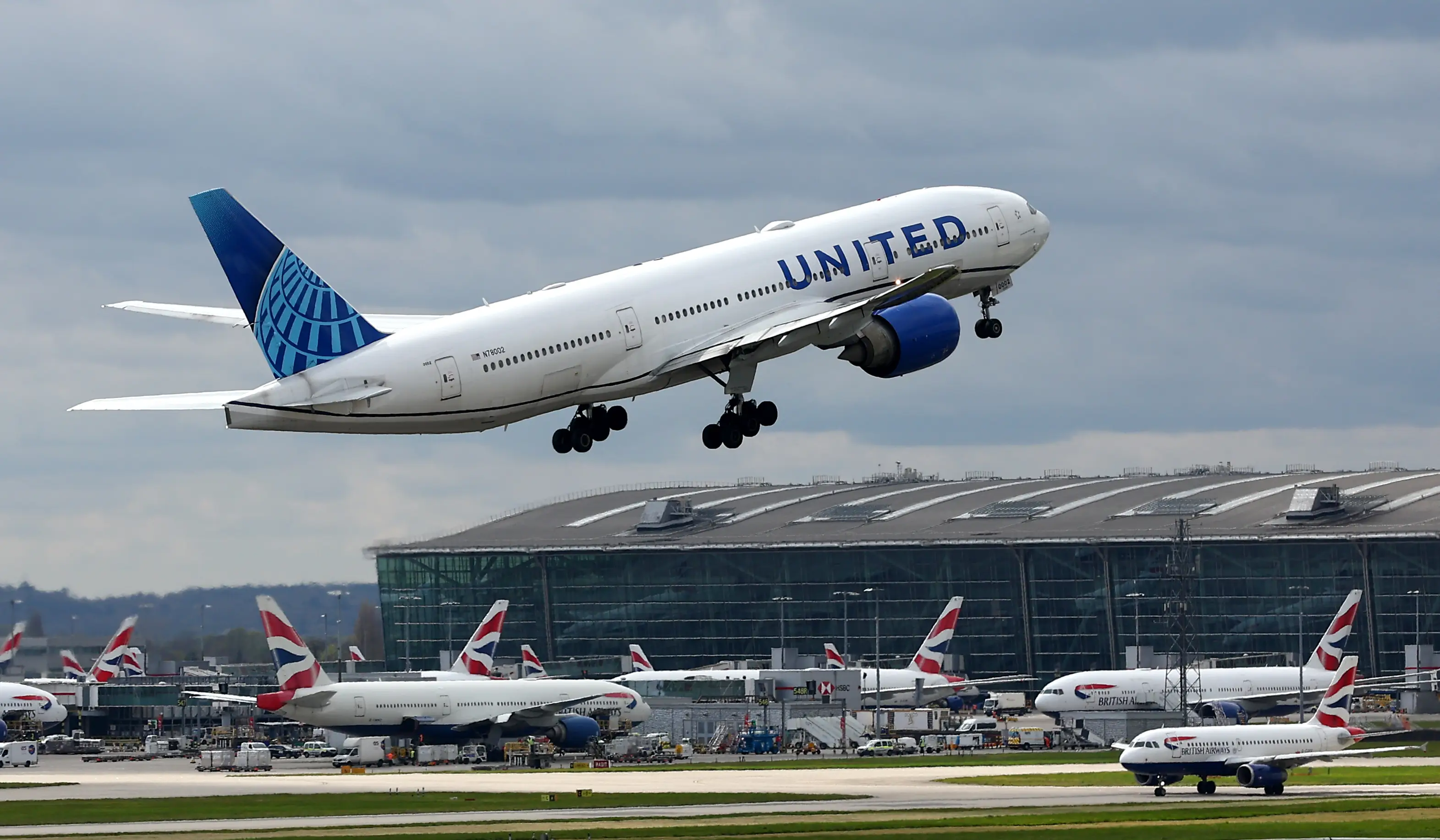 A United Airlines Boeing 777 airplane takes off from Heathrow Airport against a blue, cloudy sky.