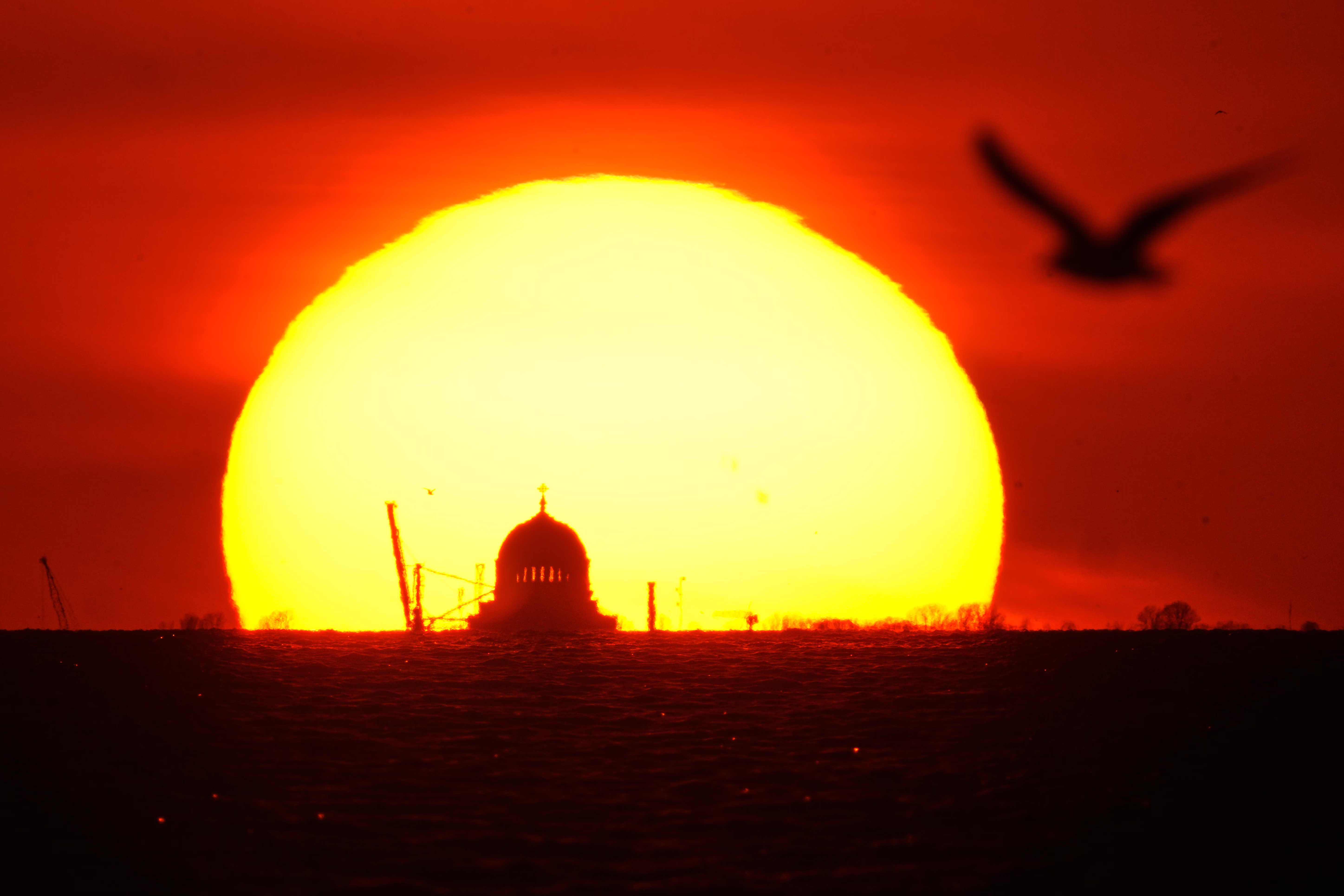 The sun sets behind a distant cathedral.