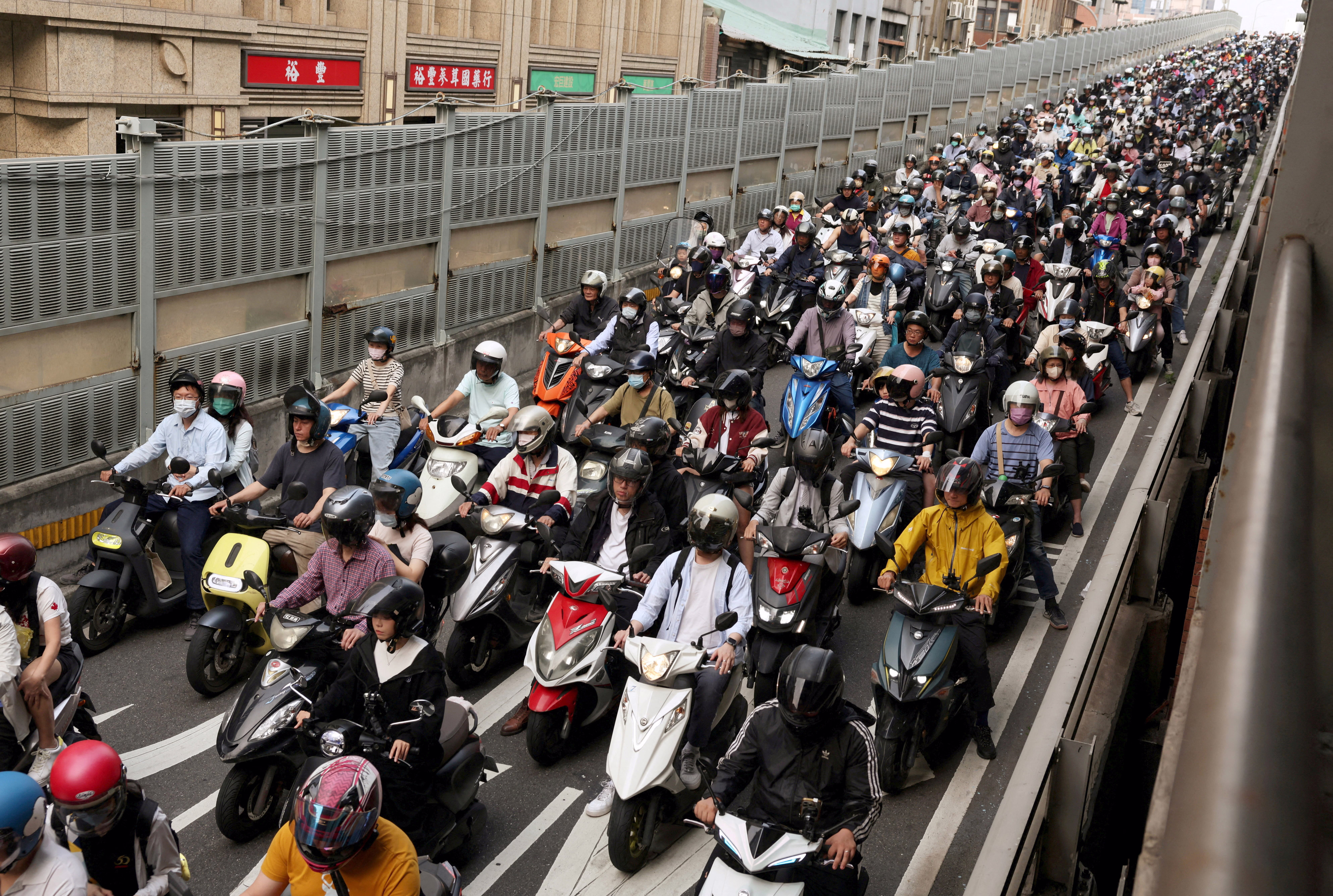Dozens of people on scooters fill a highway offramp.
