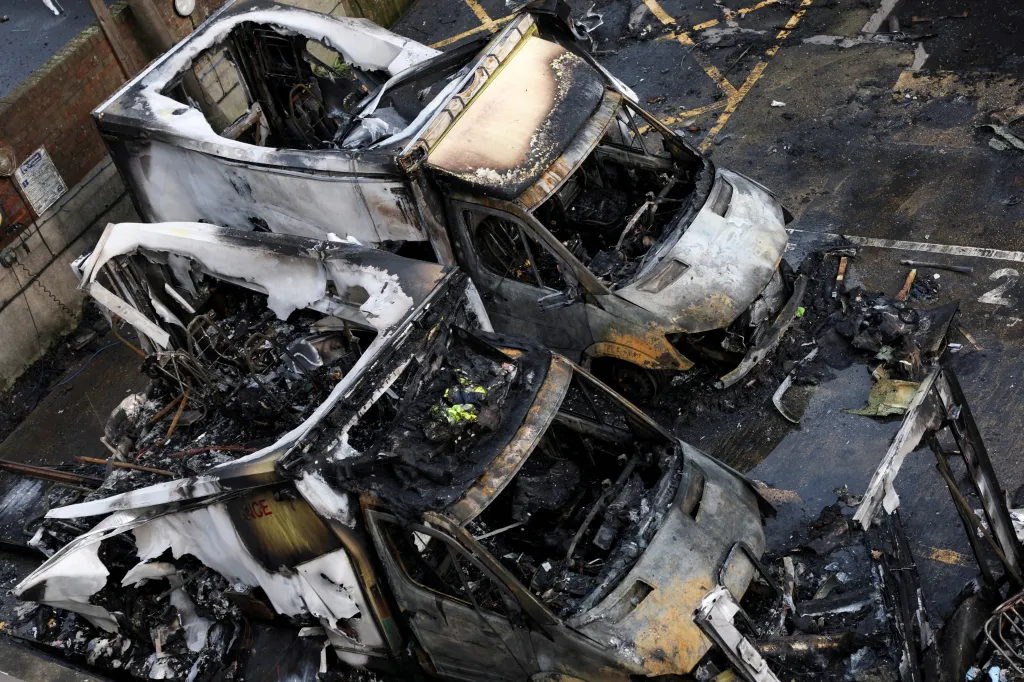 Three charred and destroyed ambulances belonging to Hatzola, a Jewish community organization, sit in a parking lot.