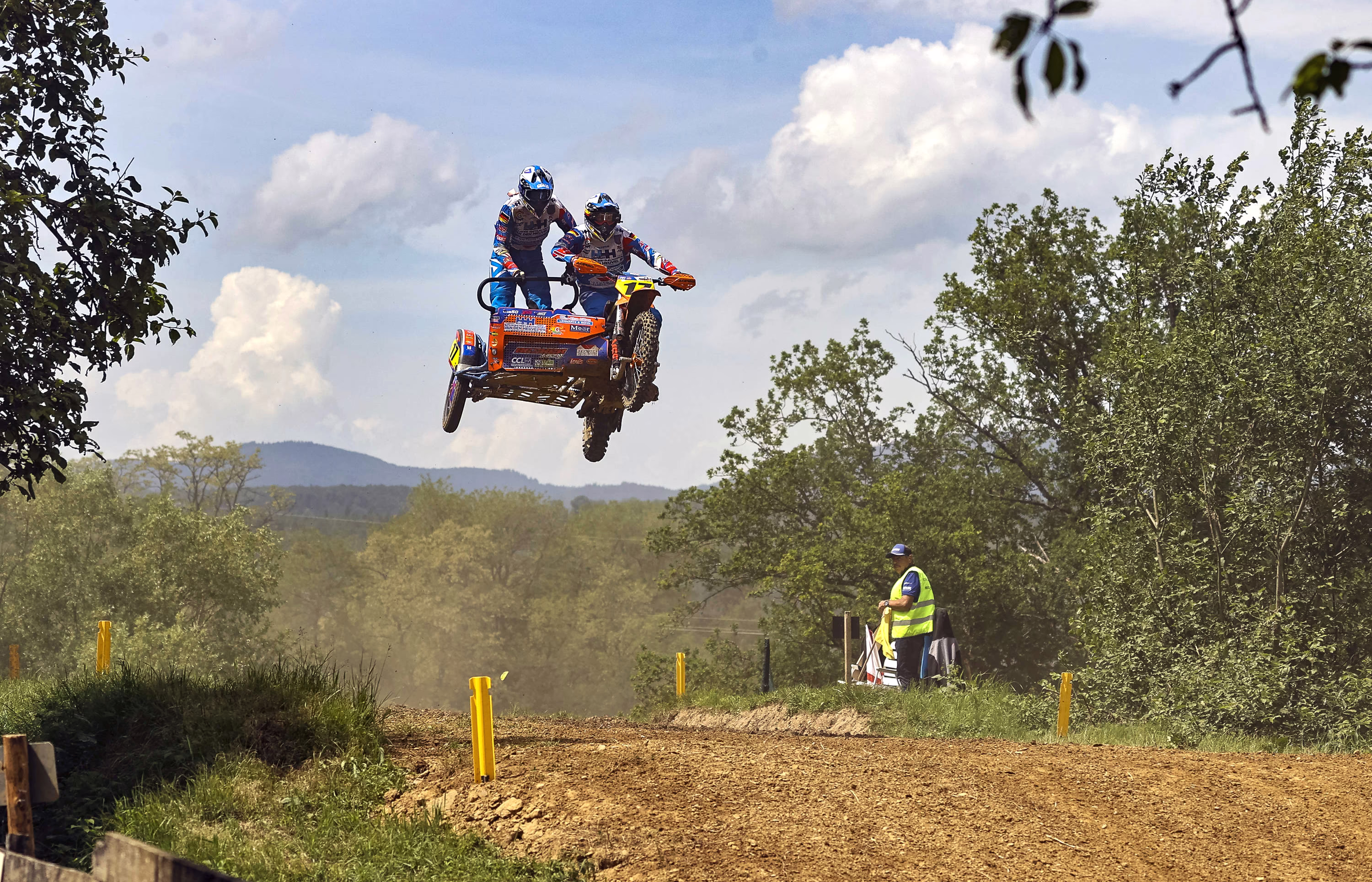Racers on a motorcycle-and-sidecar take a jump off a hill during a race.