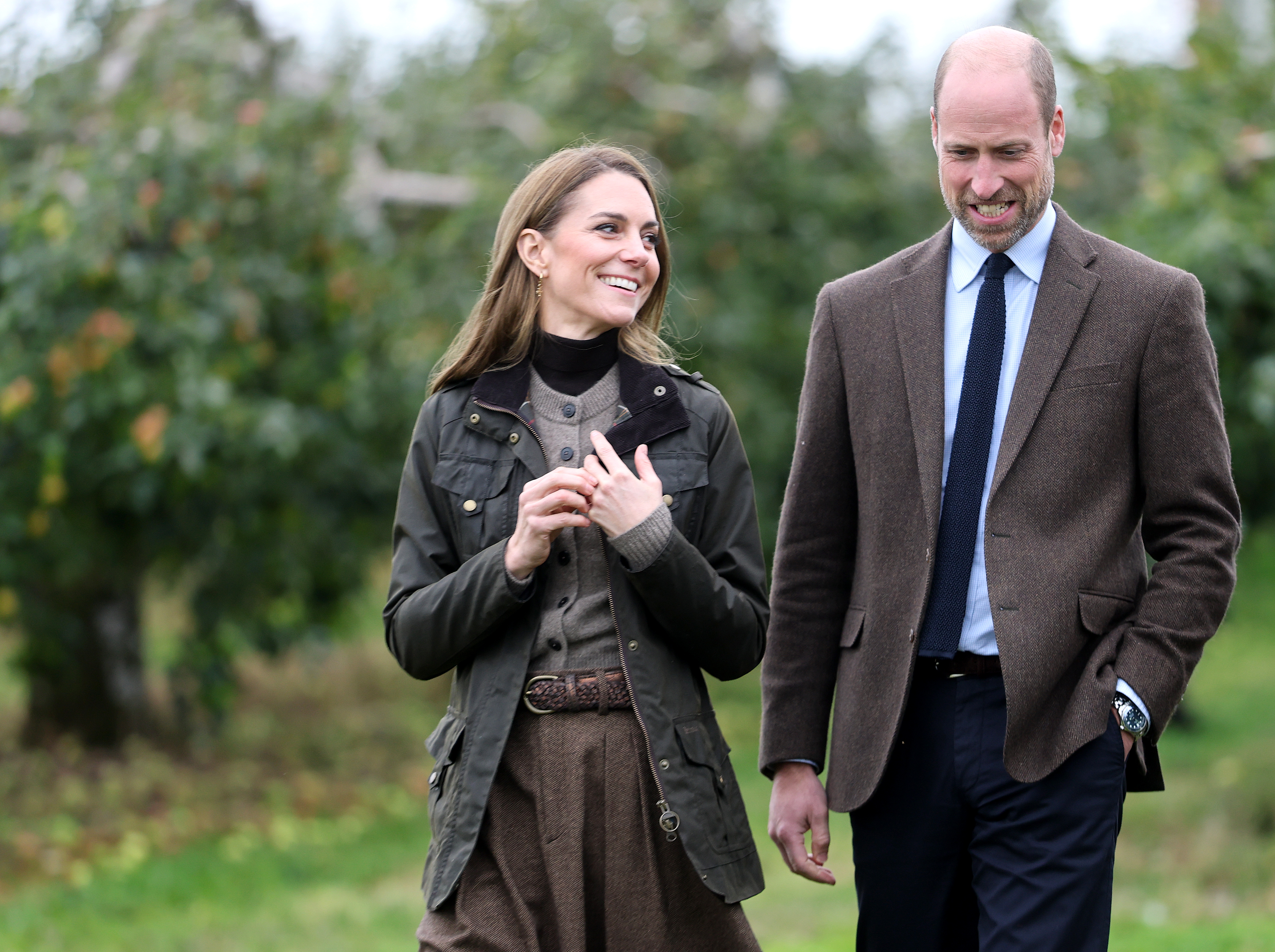 Catherine, Princess of Wales and Prince William, Prince of Wales, walking through an orchard.
