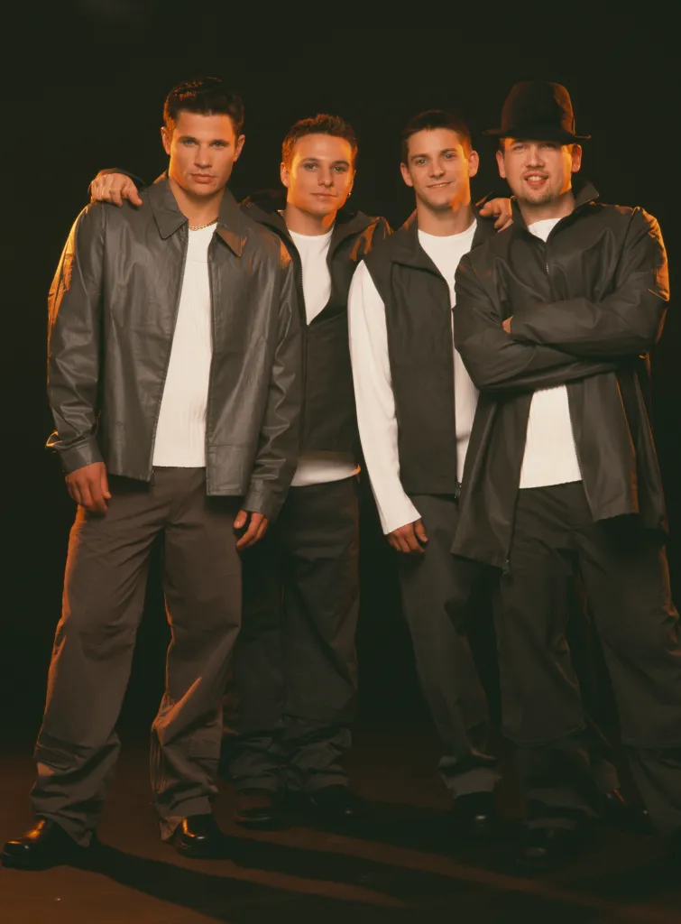 Four members of the band 98 Degrees posed in dark jackets and trousers.