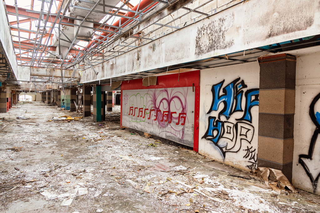 Interior of Castle Mall, a derelict entertainment park, with rubble on the floor and graffiti on the walls.