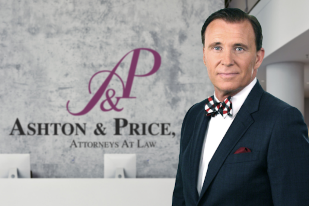 A man in a suit and bow tie stands in front of a wall with the 