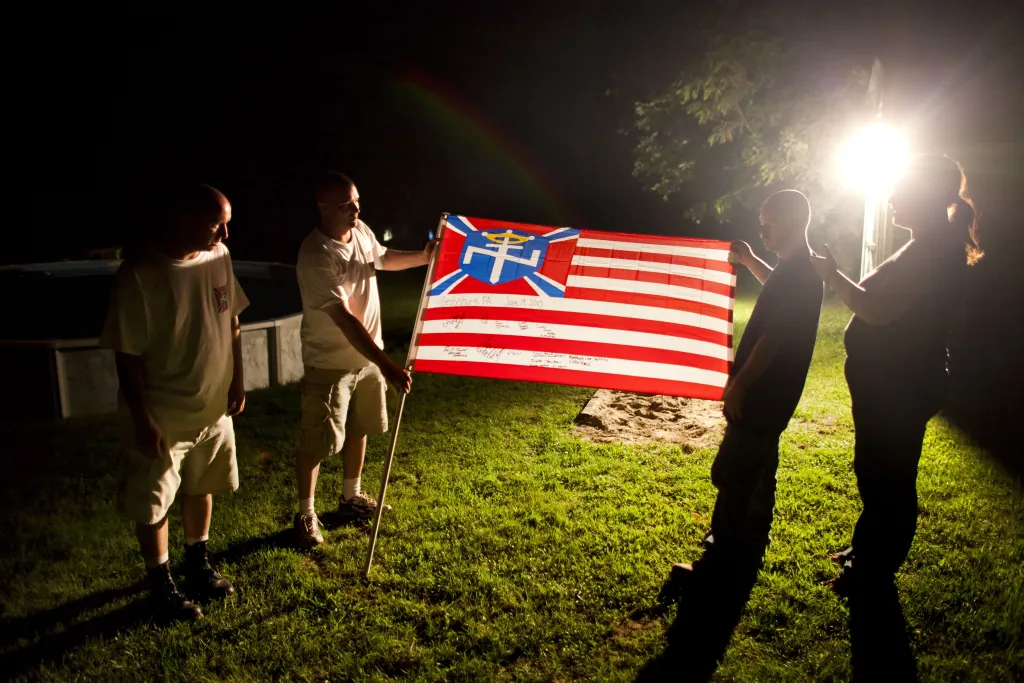 Members of the Aryan Nations display a white nationalist flag.