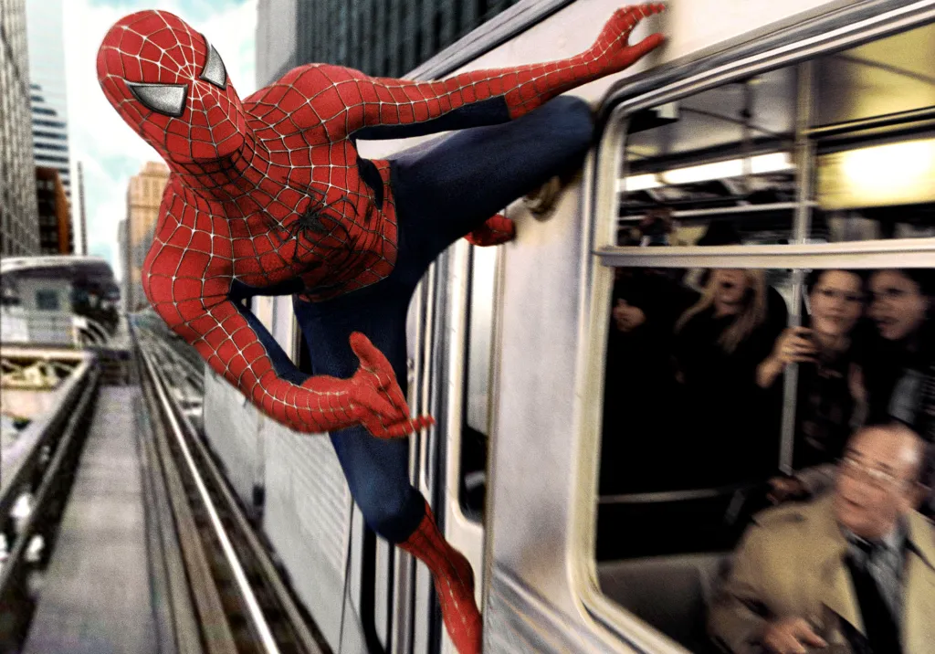 Spider-Man clinging to the side of a moving train as passengers look on.