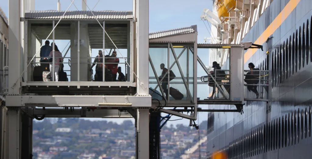 Passengers disembarking from a cruise ship via gangways.