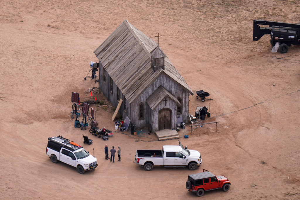 Aerial photo of the Bonanza Creek Ranch film set in Santa Fe, N.M., showing a wooden church, film equipment, trucks, and three people.