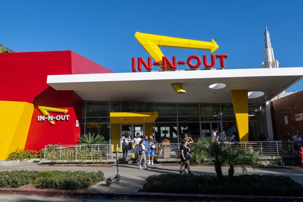 People walking out of an In-N-Out in Westwood, Los Angeles, with a large red and yellow building and the In-N-Out sign prominently displayed.