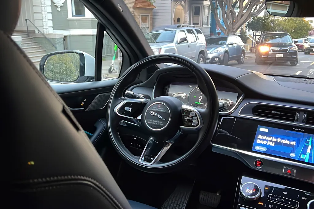 Interior view of a Waymo driverless taxi, showing the steering wheel with a 
