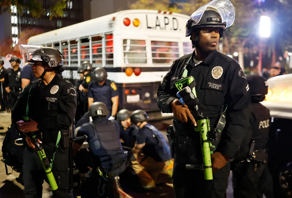 LAPD officers monitoring a detained person near City Hall after immigration raids in Los Angeles.