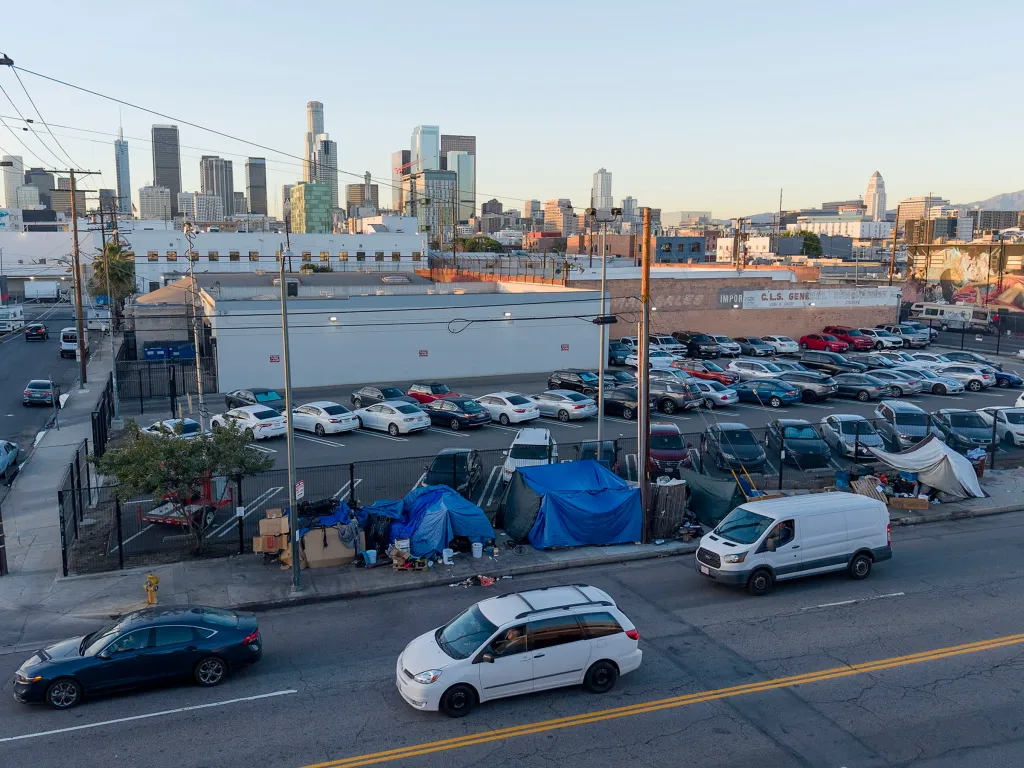 Homeless encampments in Downtown Los Angeles with the city skyline in the background.