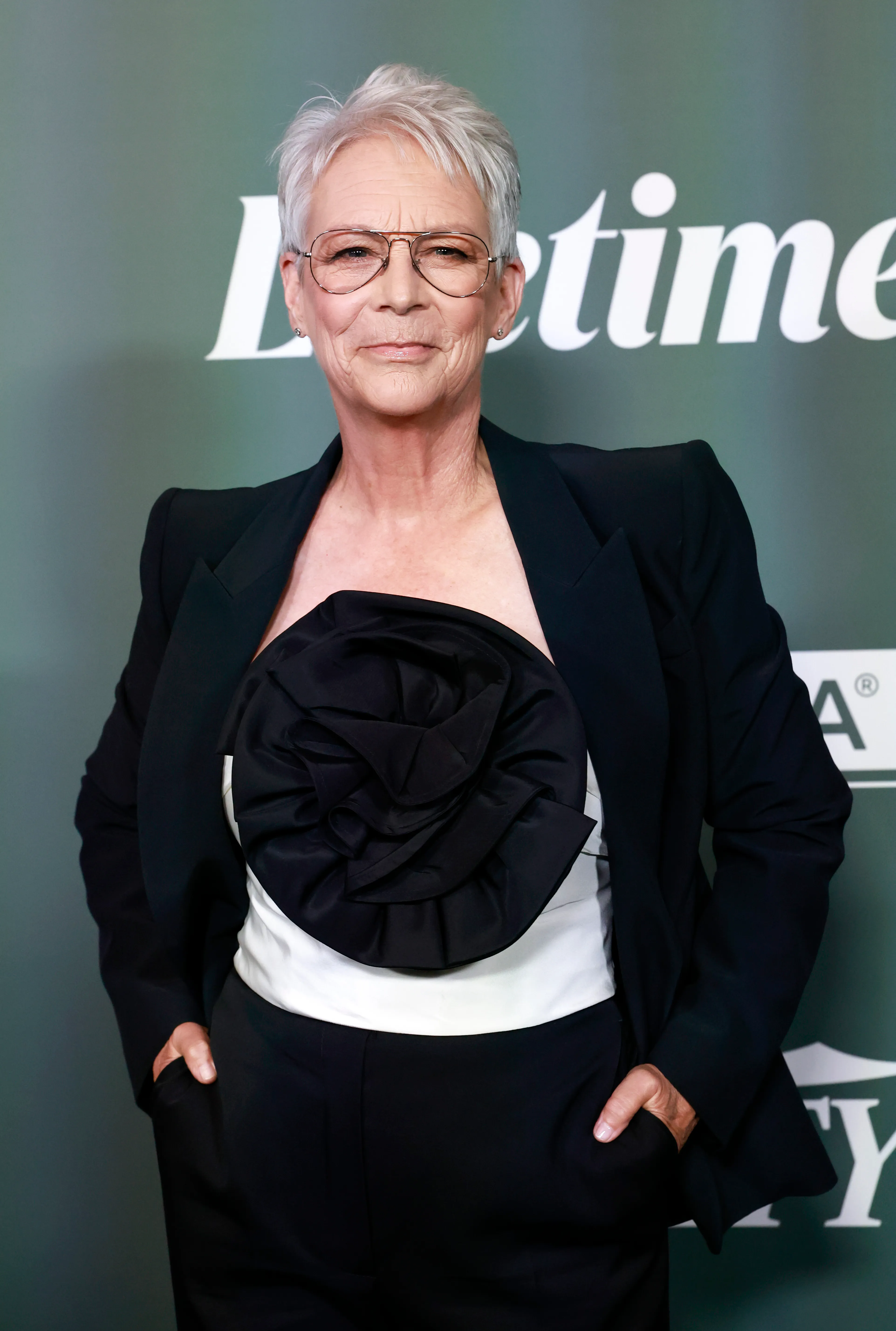 Jamie Lee Curtis in a black blazer and white top with a large black floral embellishment at Variety's 2025 Power of Women event.