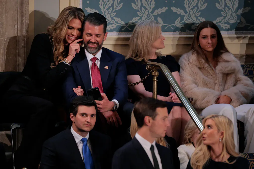 Bettina Anderson tickles Donald Trump Jr.'s face as they sit in the U.S. Capitol, with other attendees in the foreground and background.