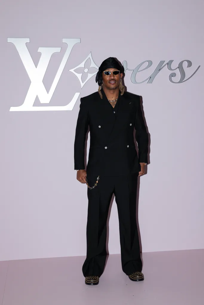 US rapper Future poses in a black suit with a black durag and sunglasses against a pink wall with Louis Vuitton
