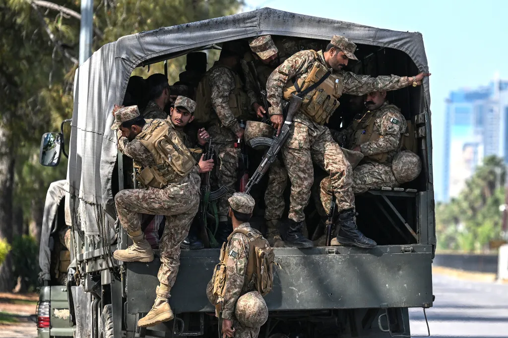 Pakistani army soldiers in camouflage uniform and carrying weapons deploy from the back of a military truck in Islamabad.