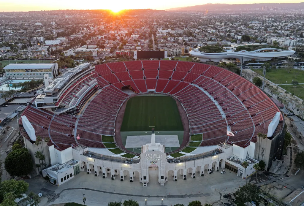 Aerial view of Los Angeles Memorial Coliseum and the Lucas Museum of Narrative Art (R) in Exposition Park at sunset.