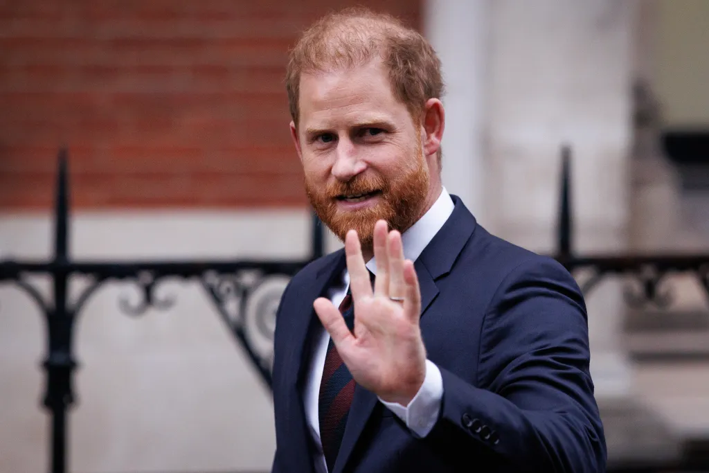Prince Harry, Duke of Sussex, smiles and waves to the camera.