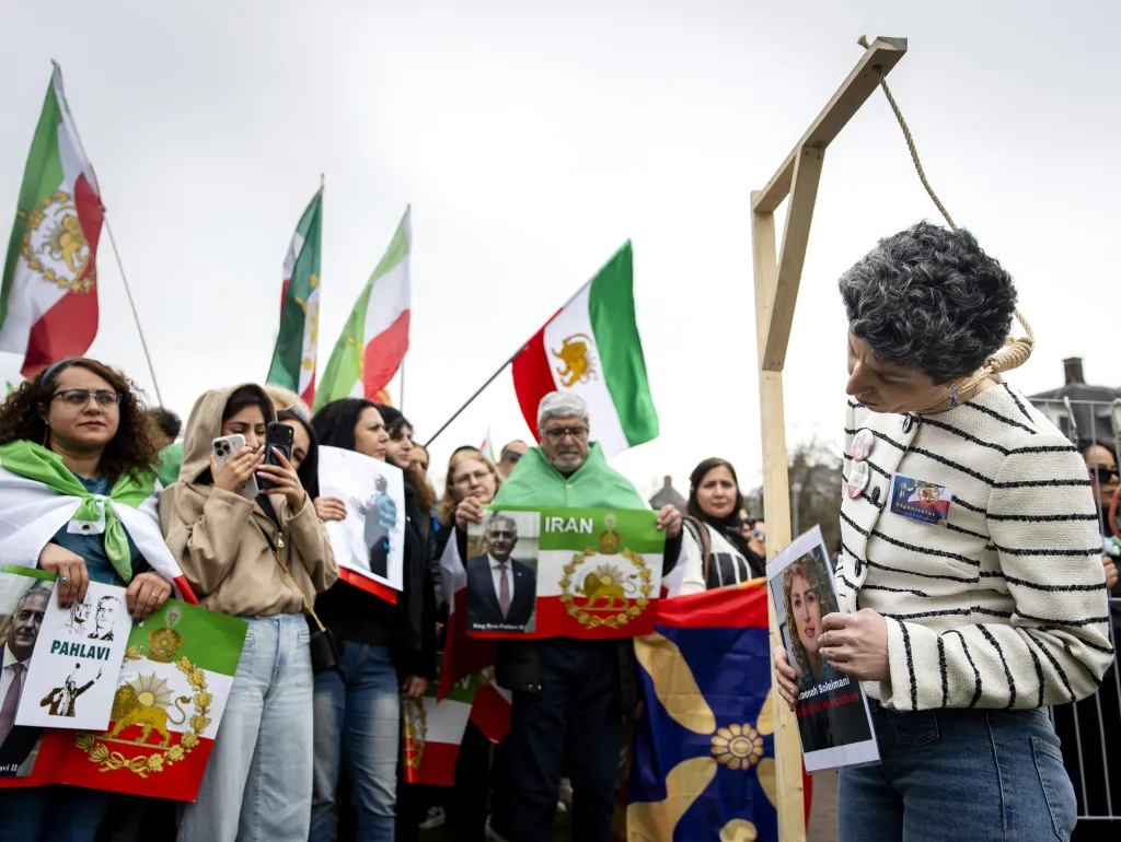Protesters at a demonstration against the Iranian regime in Amsterdam, with Iranian flags and one demonstrator holding a noose around their neck.