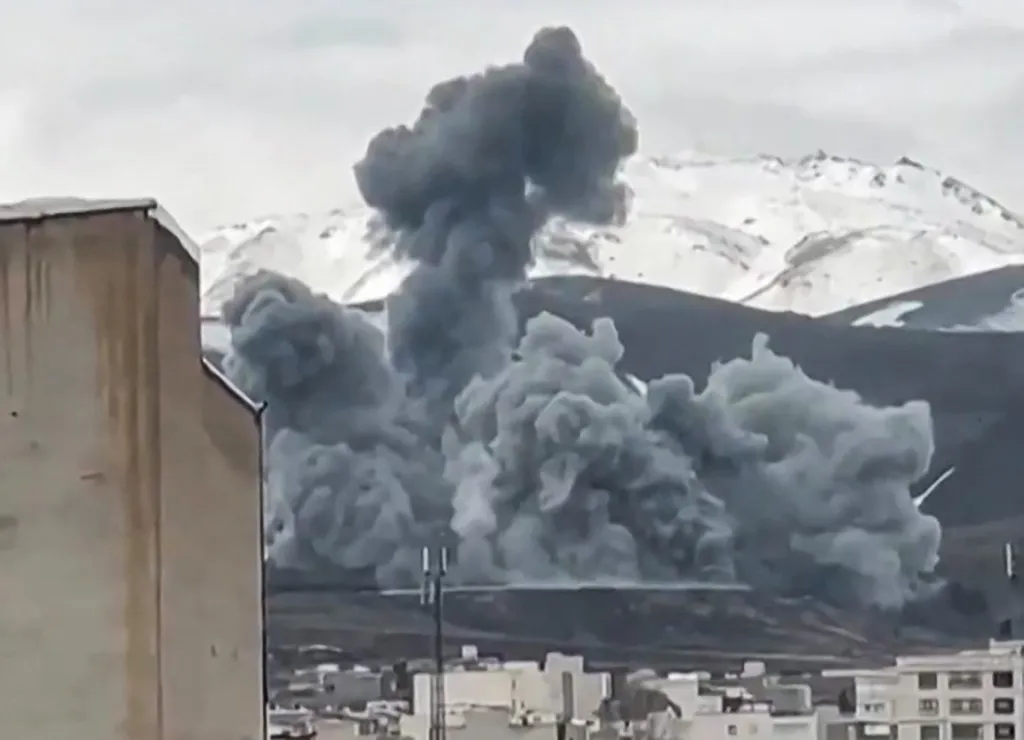 Smoke rises from the side of a snowy mountain in Hamedan, western Iran.