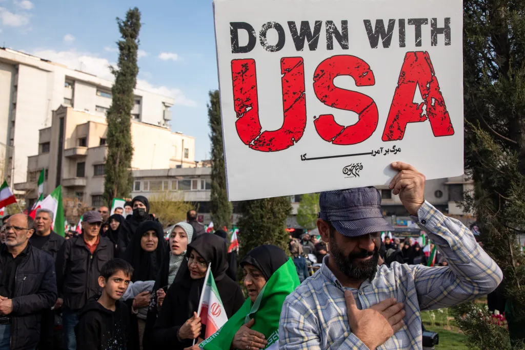 A man at a funeral procession holding an anti-American sign that reads 