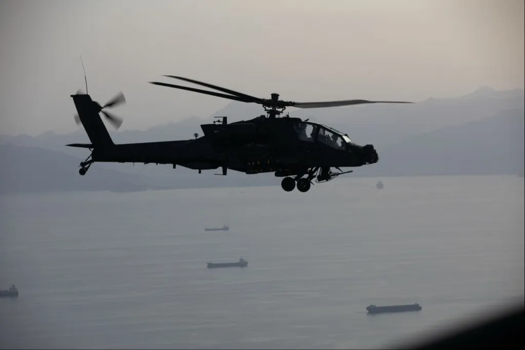 U.S. AH-64 Apache helicopter flying above the Strait of Hormuz during blockade operations.