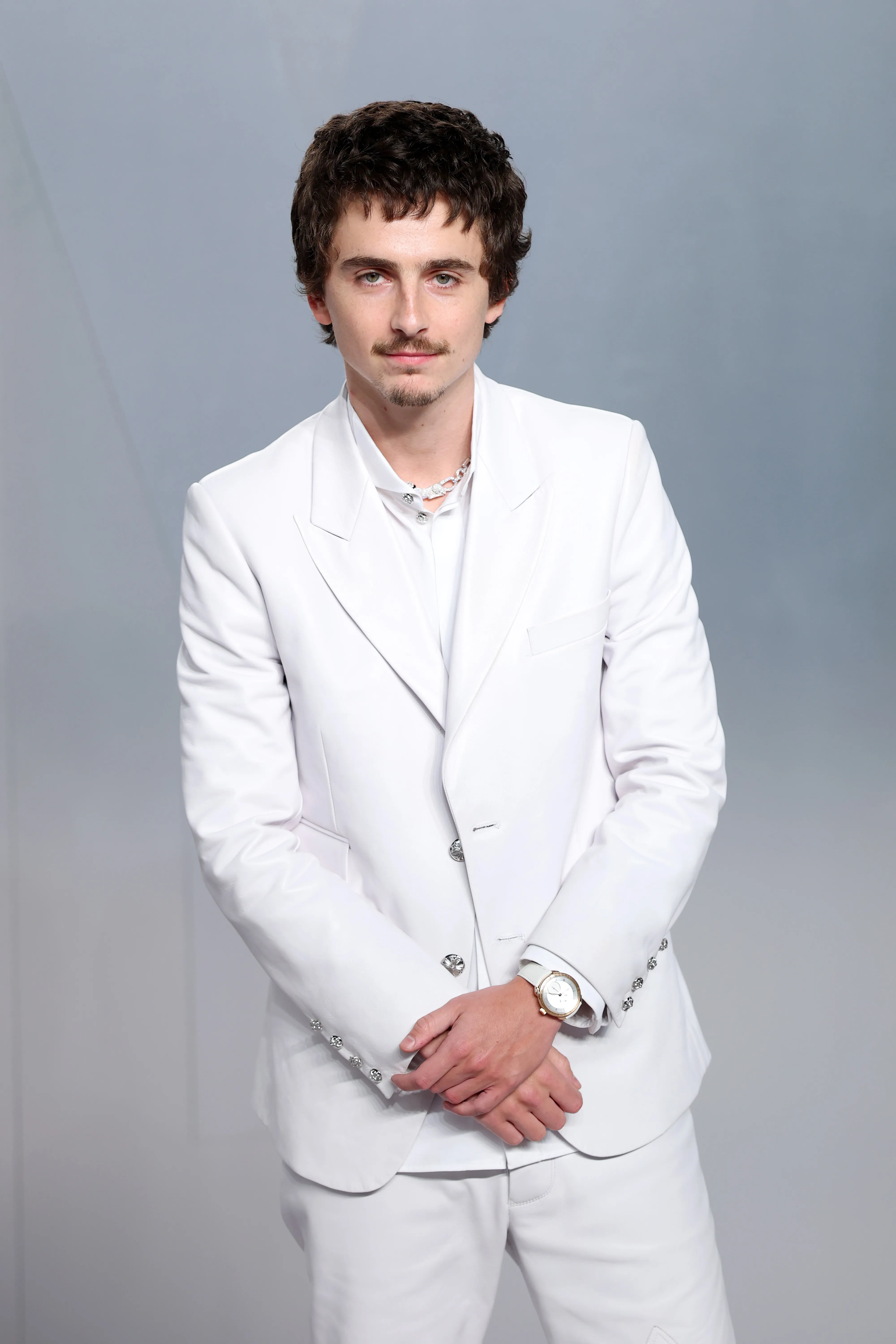 Timothée Chalamet in a white suit with a necklace and watch at the 2026 Vanity Fair Oscar Party.