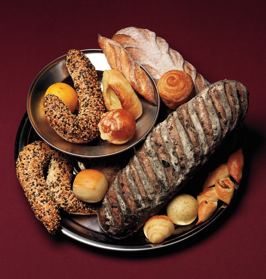 photo of many different types of breads and rolls on silver platters