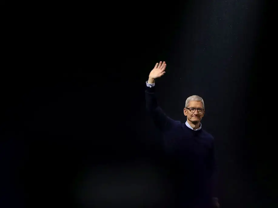 Tim Cook waving against a black background.