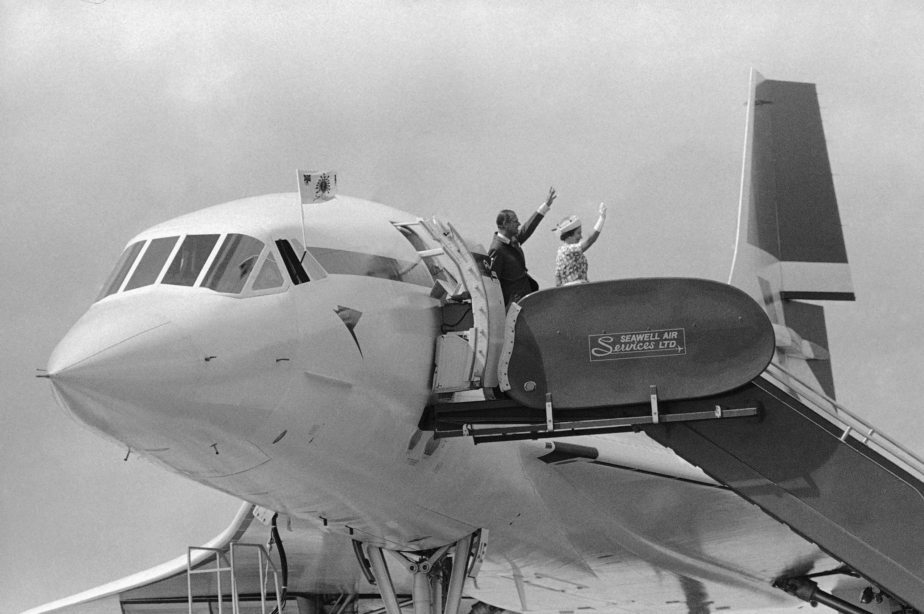 Queen Elizabeth II and Prince Philip wave from a Concorde plane.