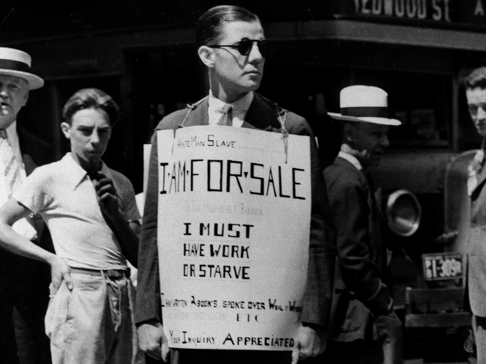 A man holding a sign during the Great Depression reading