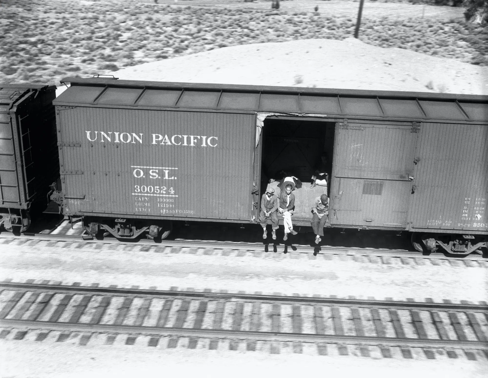 Vagrants ride a freight car on a railroad track during the Great Depression.