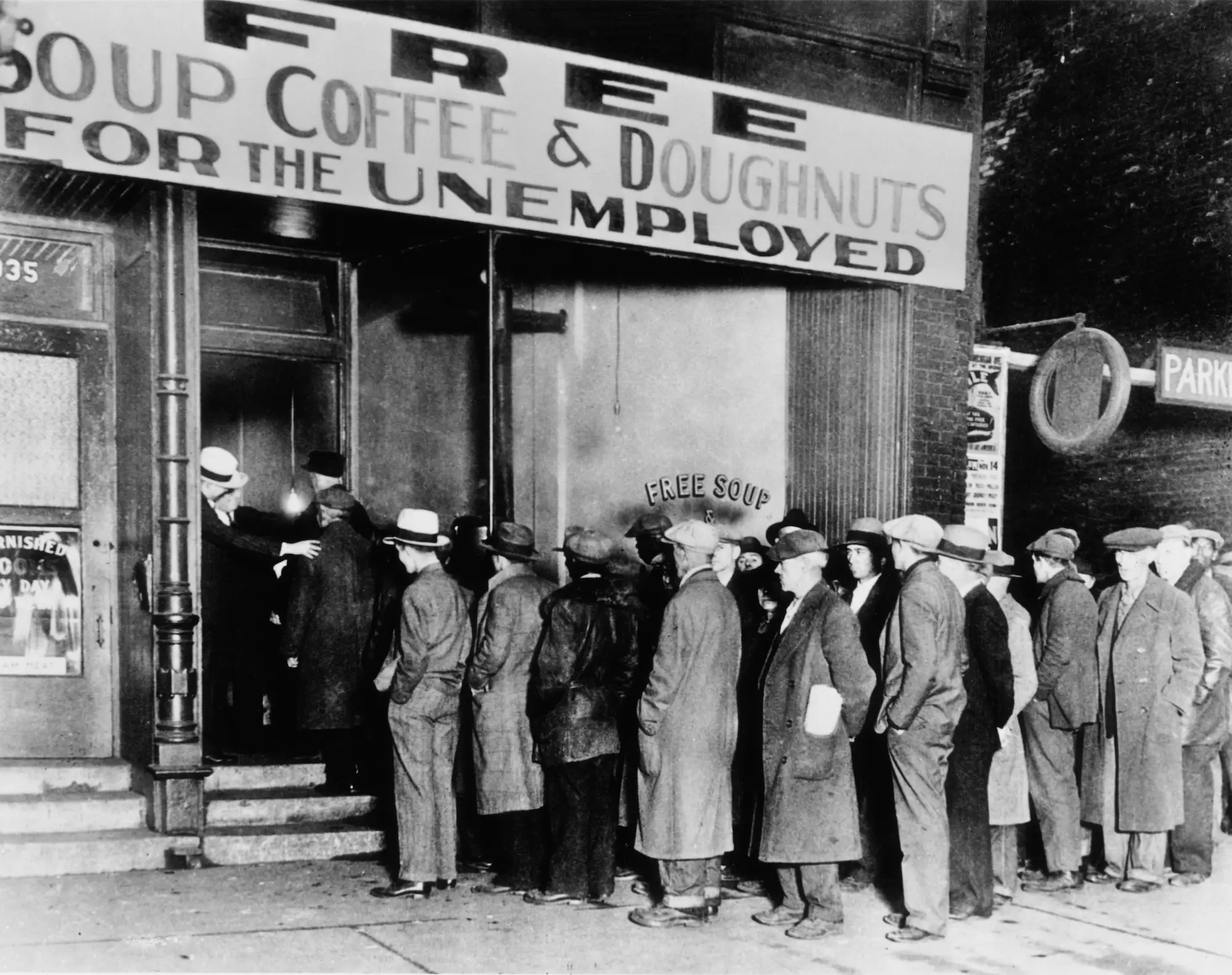 men in suits and coats stand in line under a sign that says