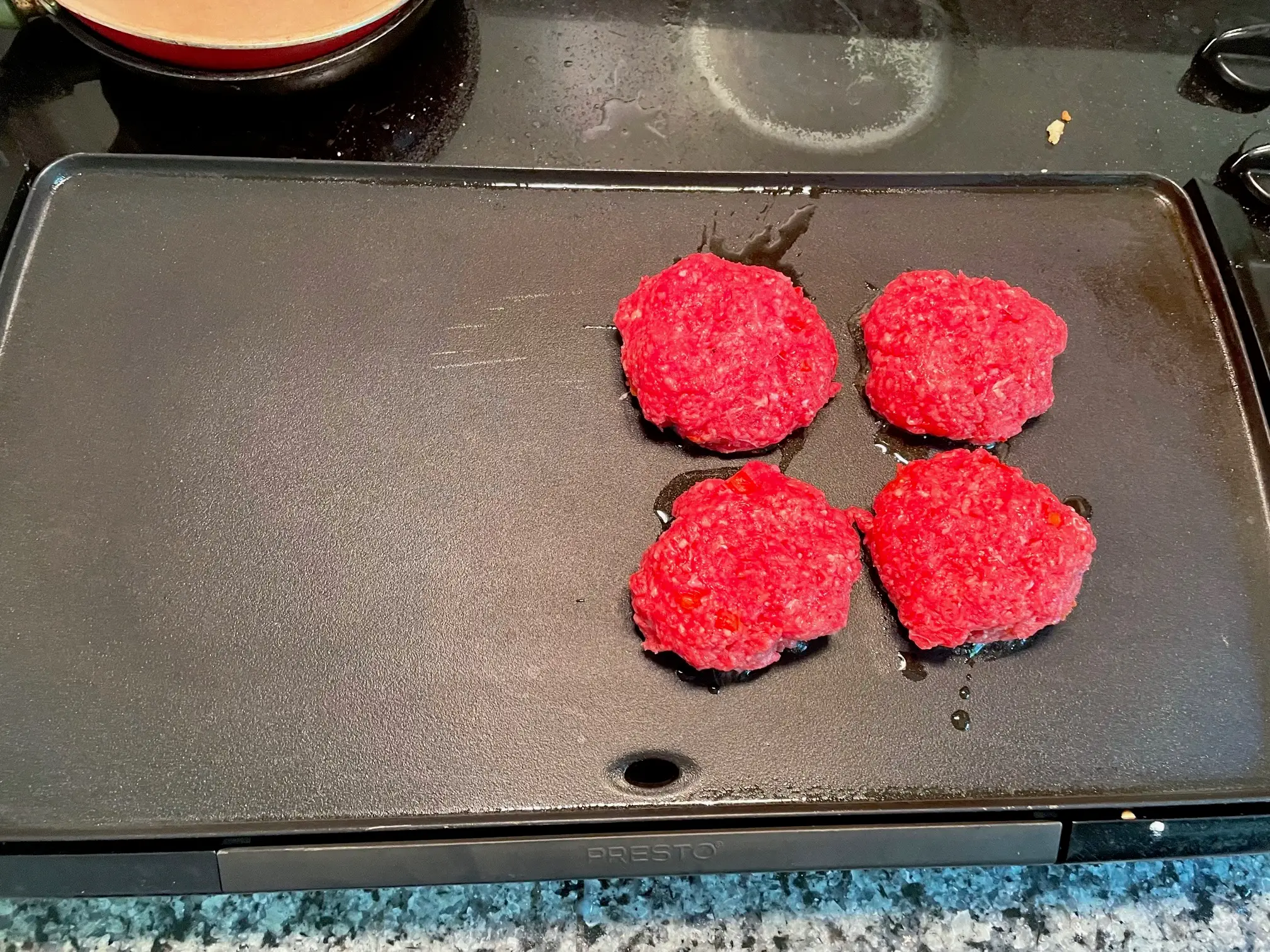 Patties on griddle for Gordon Ramsay's Burger