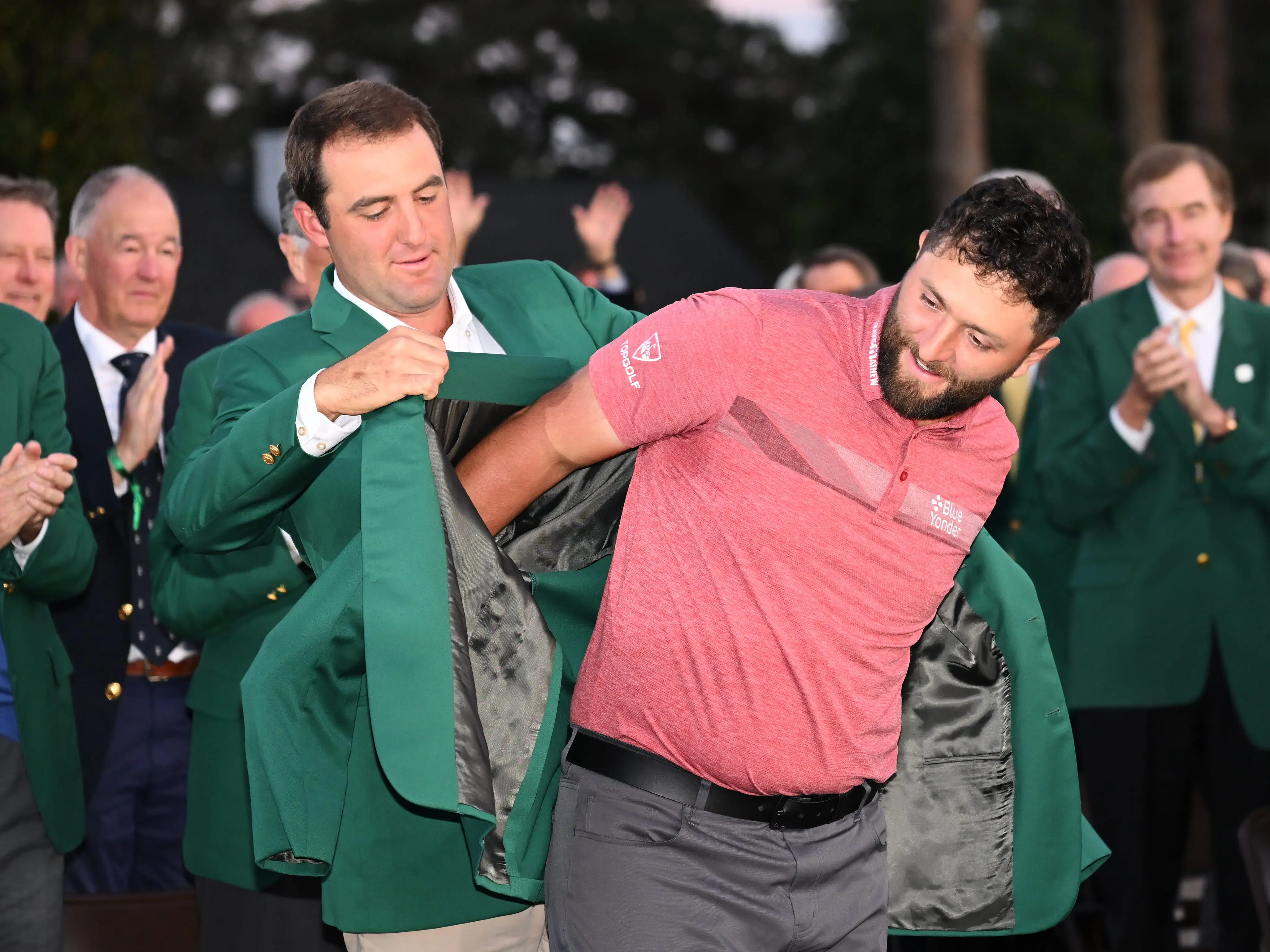 Scottie Scheffler helps 2023 Masters winner Jon Rahm with his green jacket.