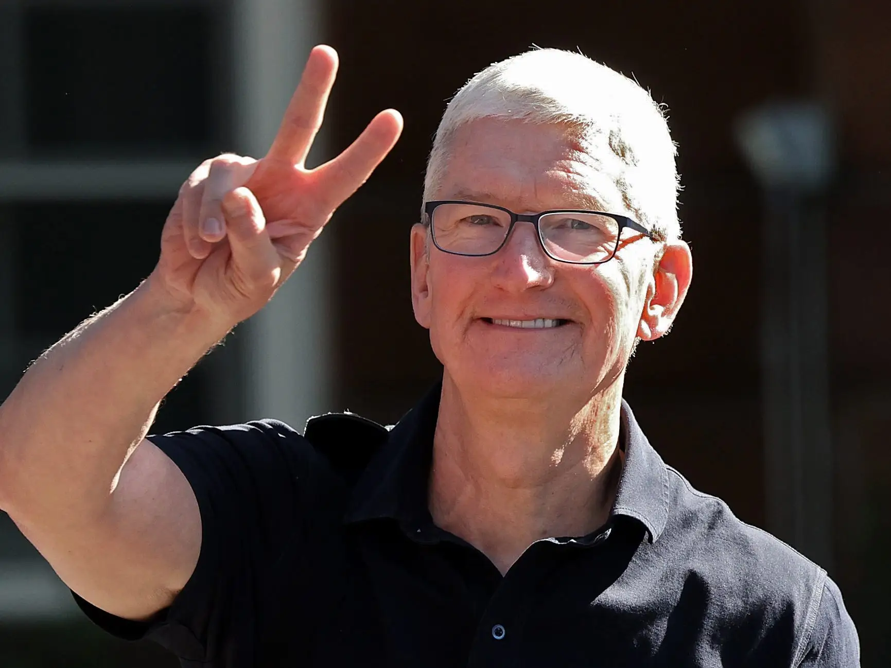 Tim Cook holding up a peace sign and smiling.