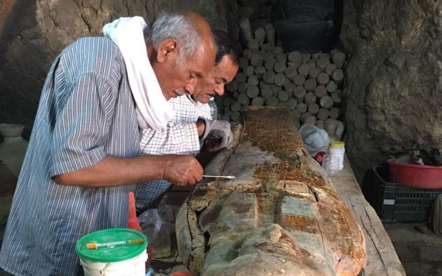 Two archaeologists examine papyrus scrolls unearthed during an excavation.