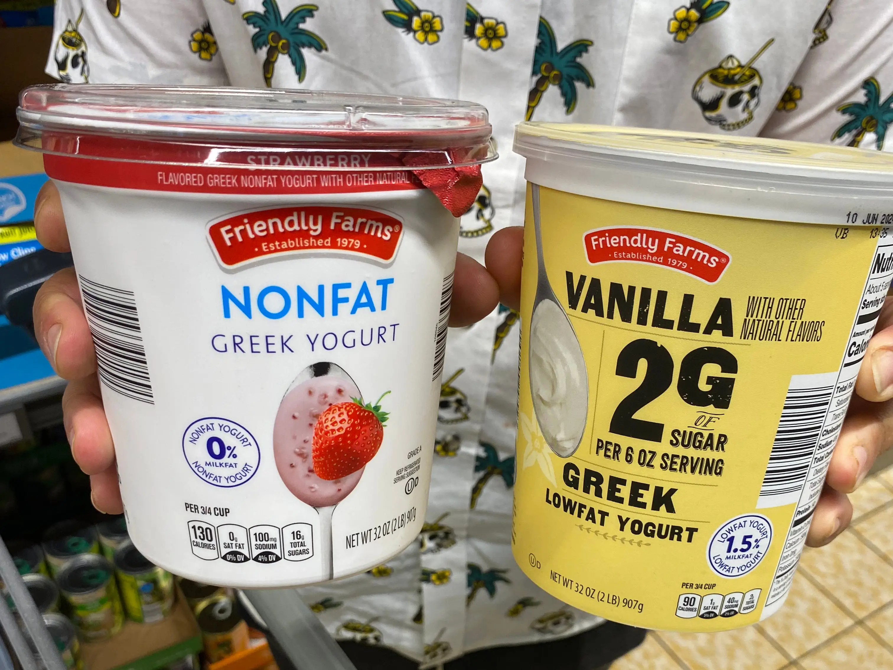hands holding up two cartons of friendly farms greek yogurt at aldi