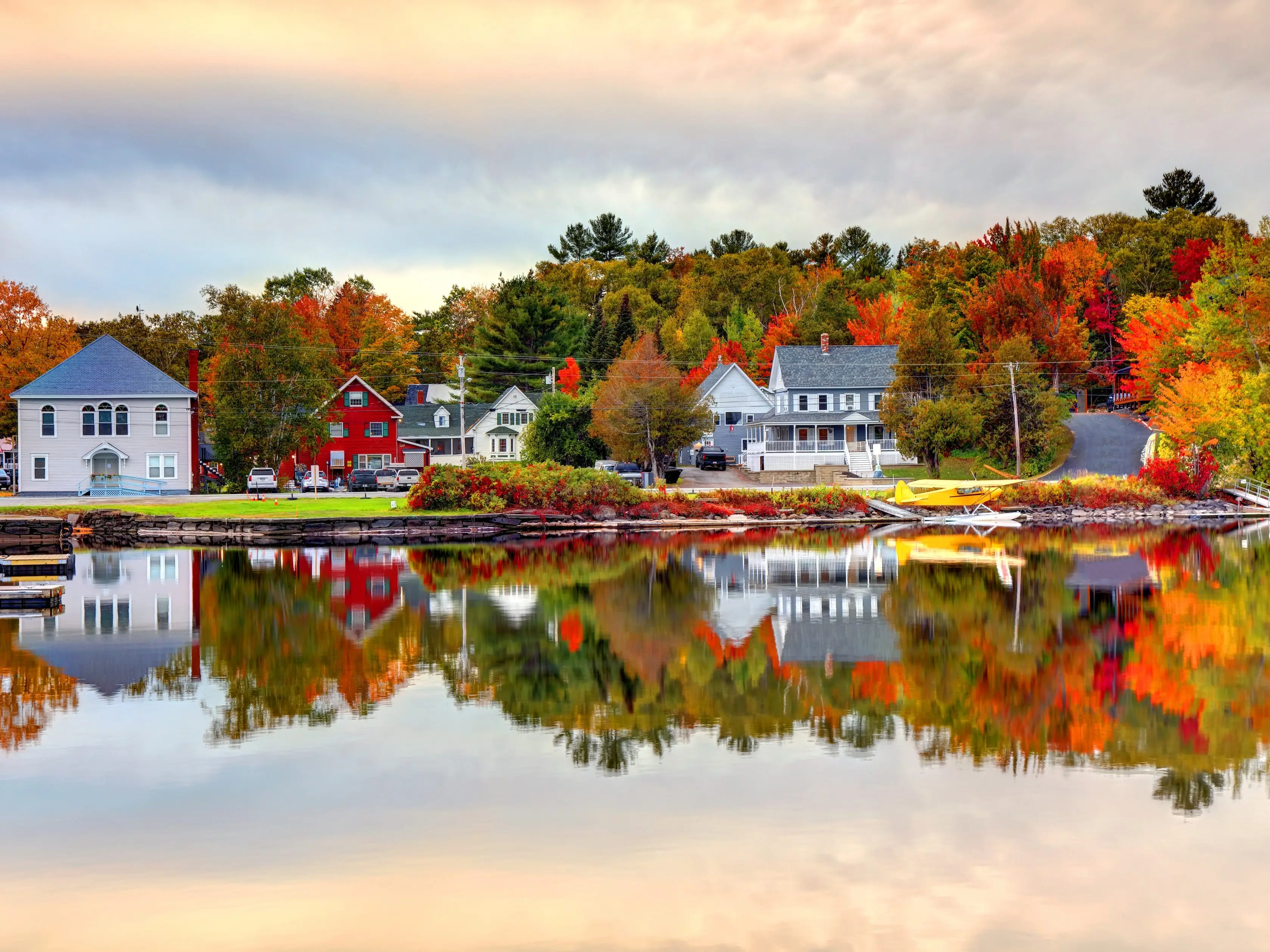 A lake surrounded by homes and fall trees reflected in the water