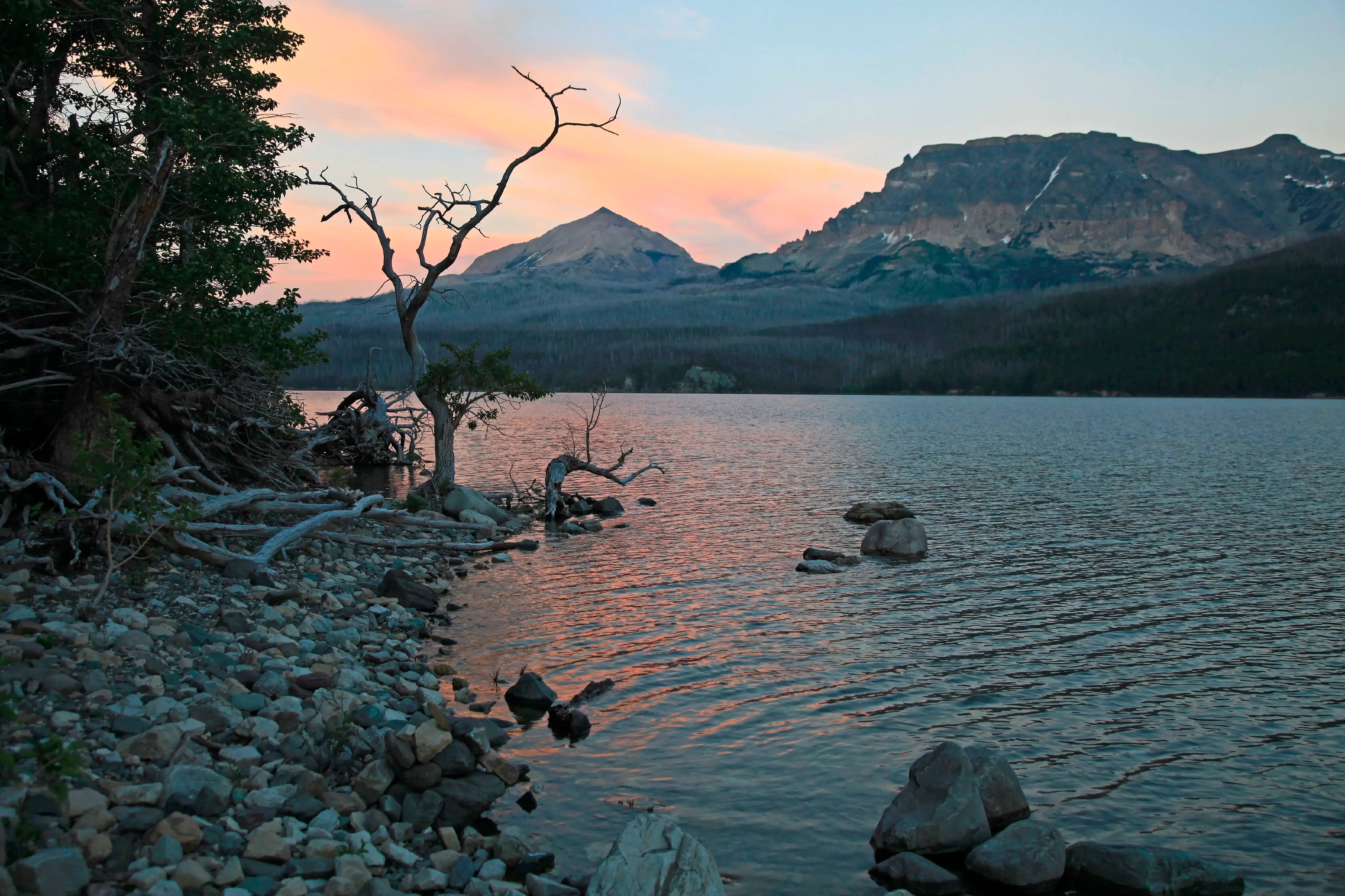 Sunset along the shoreline of Saint Mary Lake with Triple Divide Peak on the horizon in Glacier National Park Montana on a summer evening