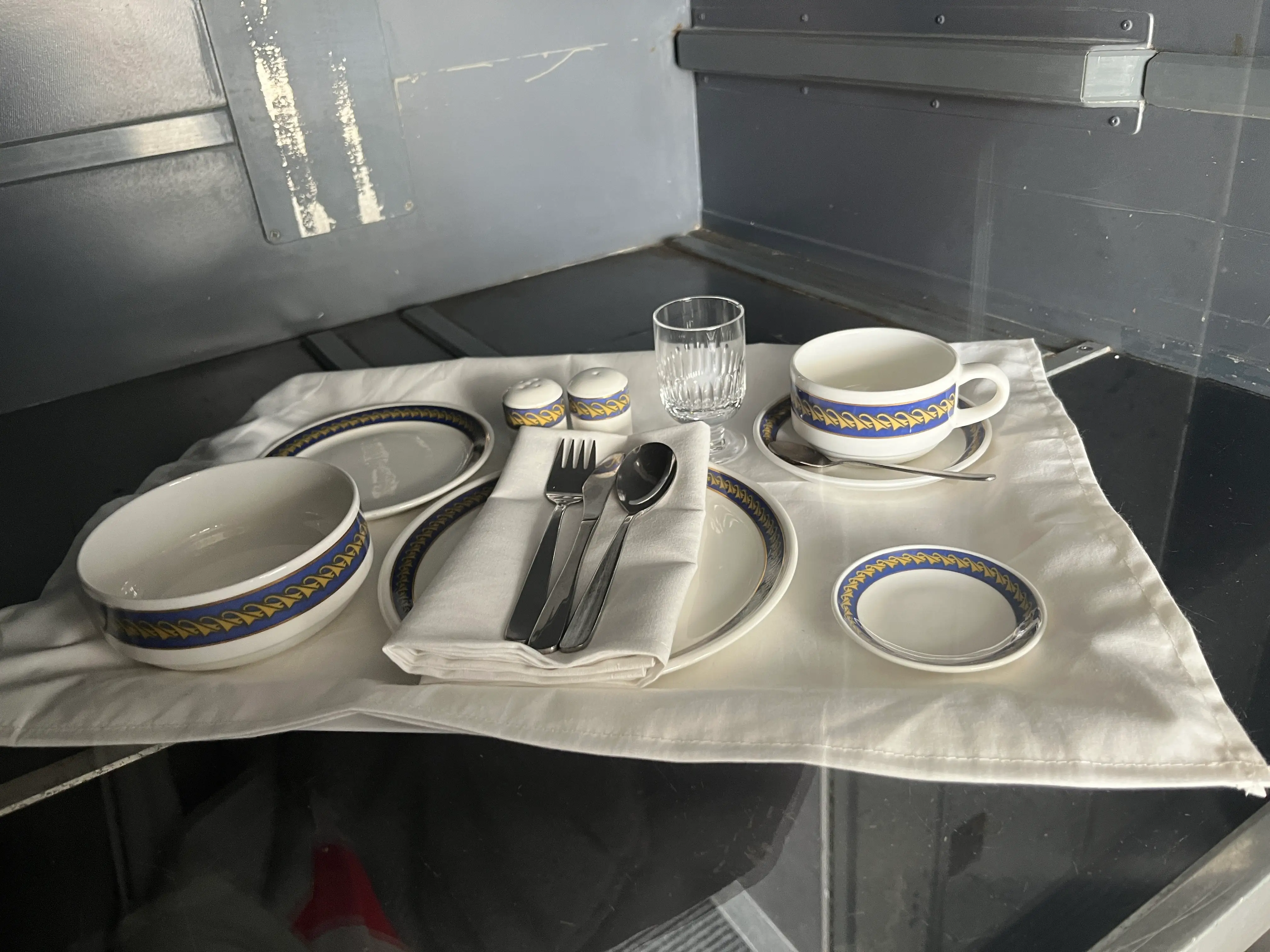 A display case with a set of dishes, cutlery, and napkins inside.