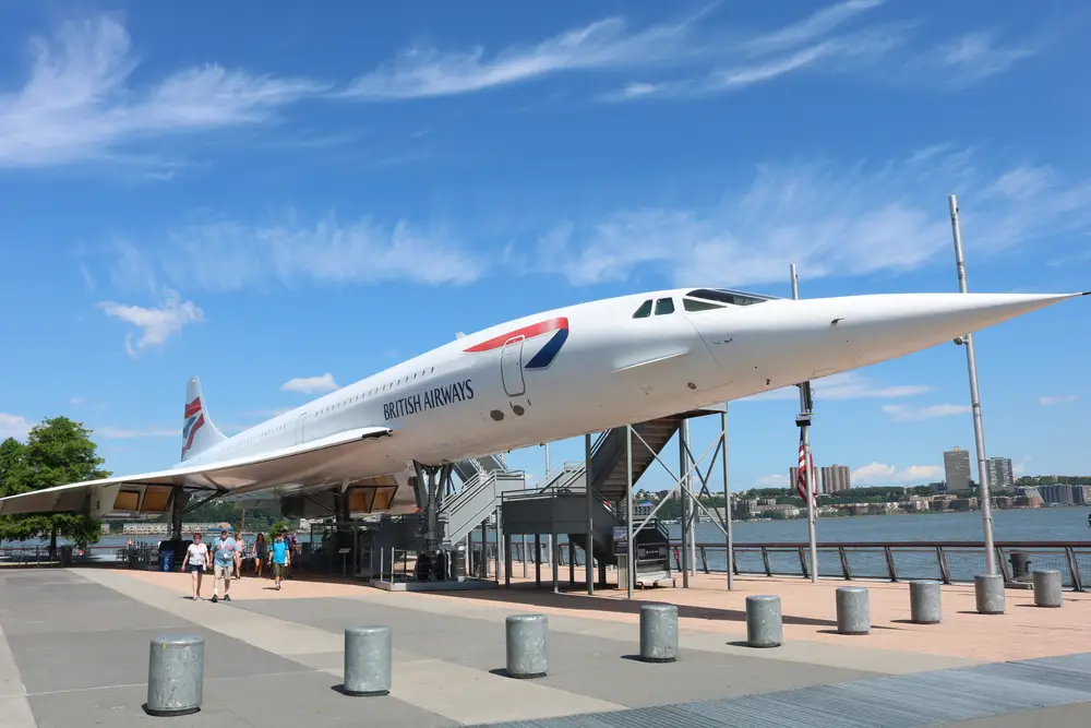 A Concorde jet with the British Airways logo on it, displayed outside.