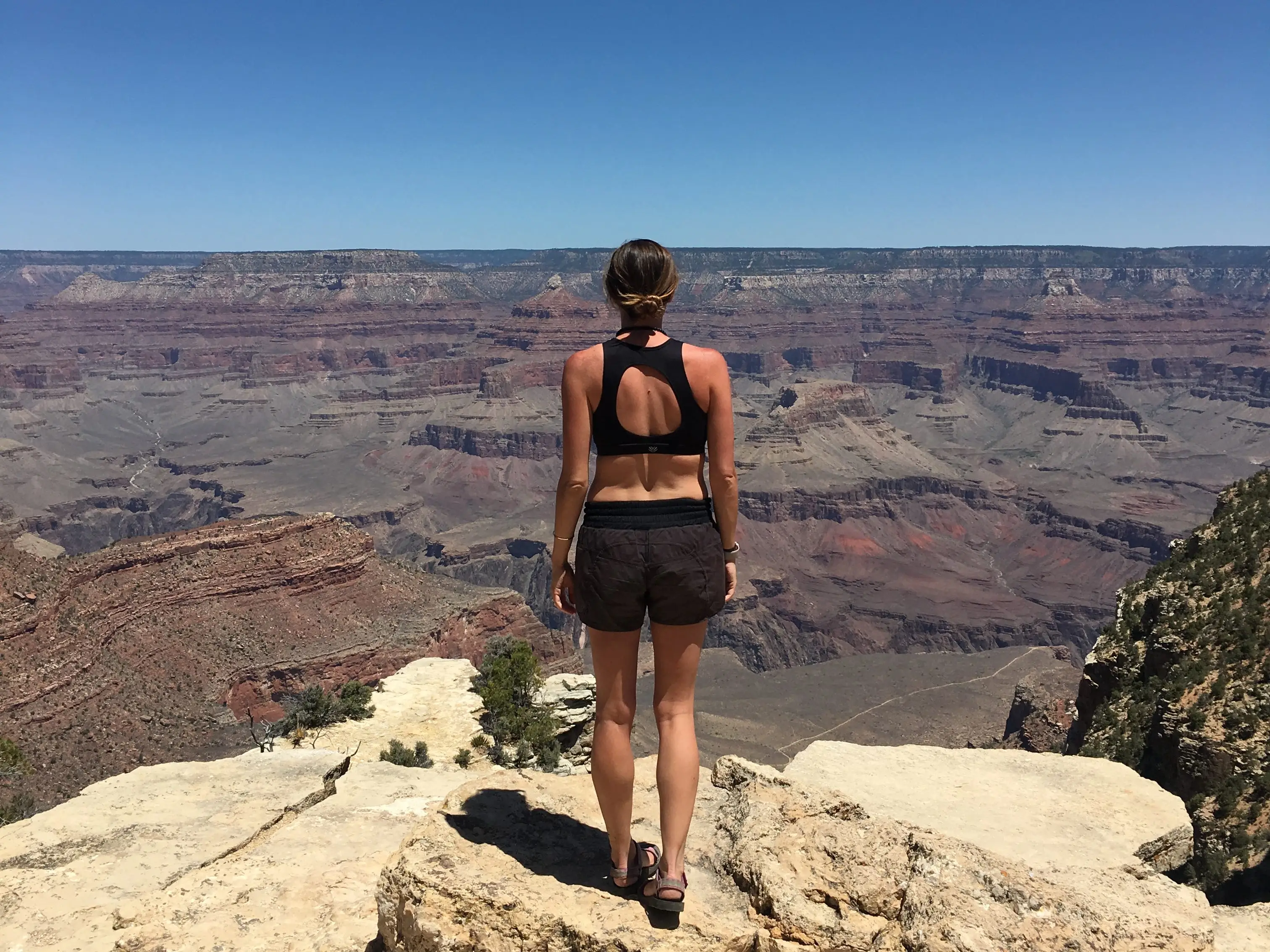Emily stands with her back to the camera, looking out at the Grand Canyon.