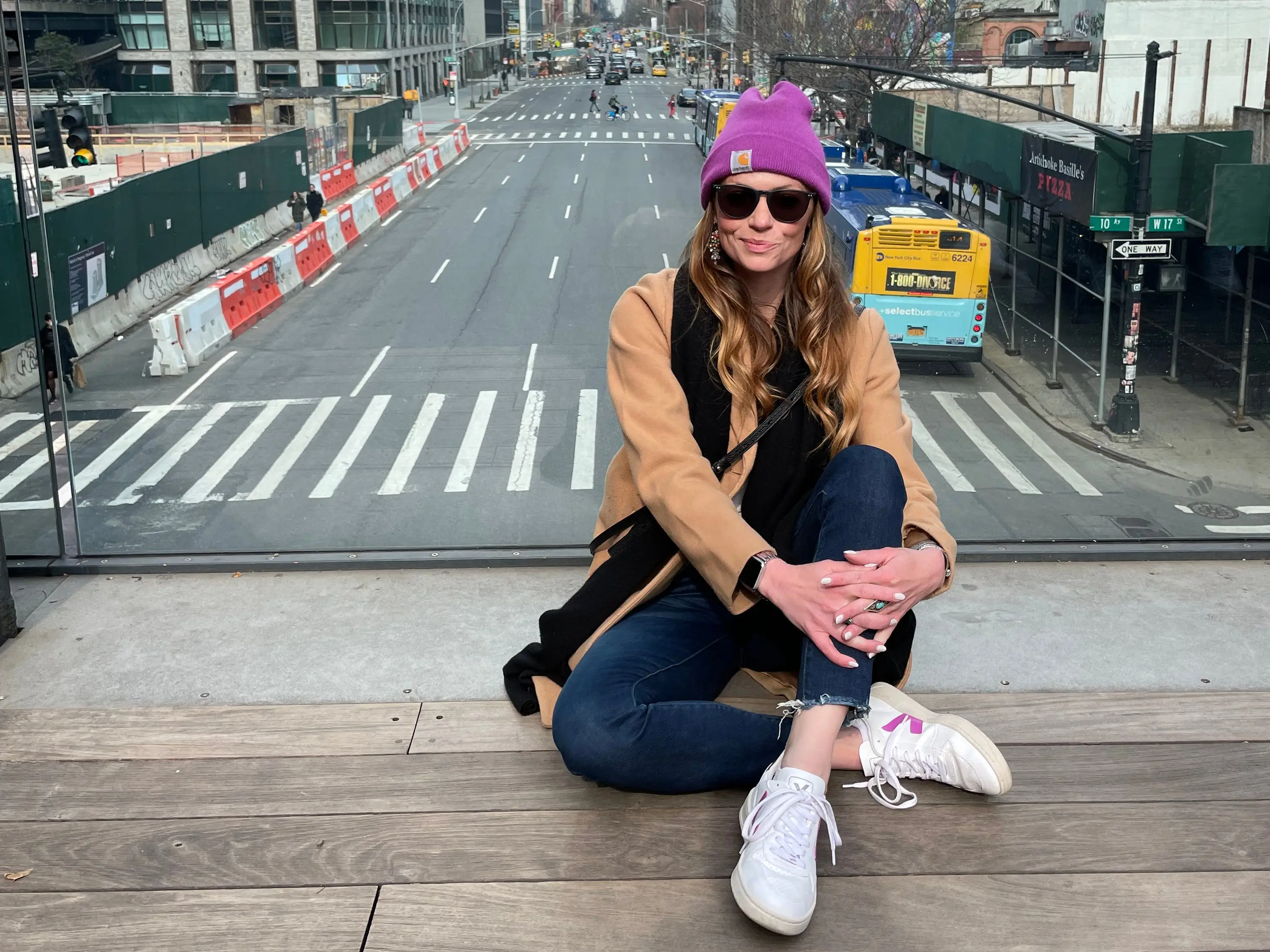 Emily sits in front of a glass window that overlooks a New York City street.
