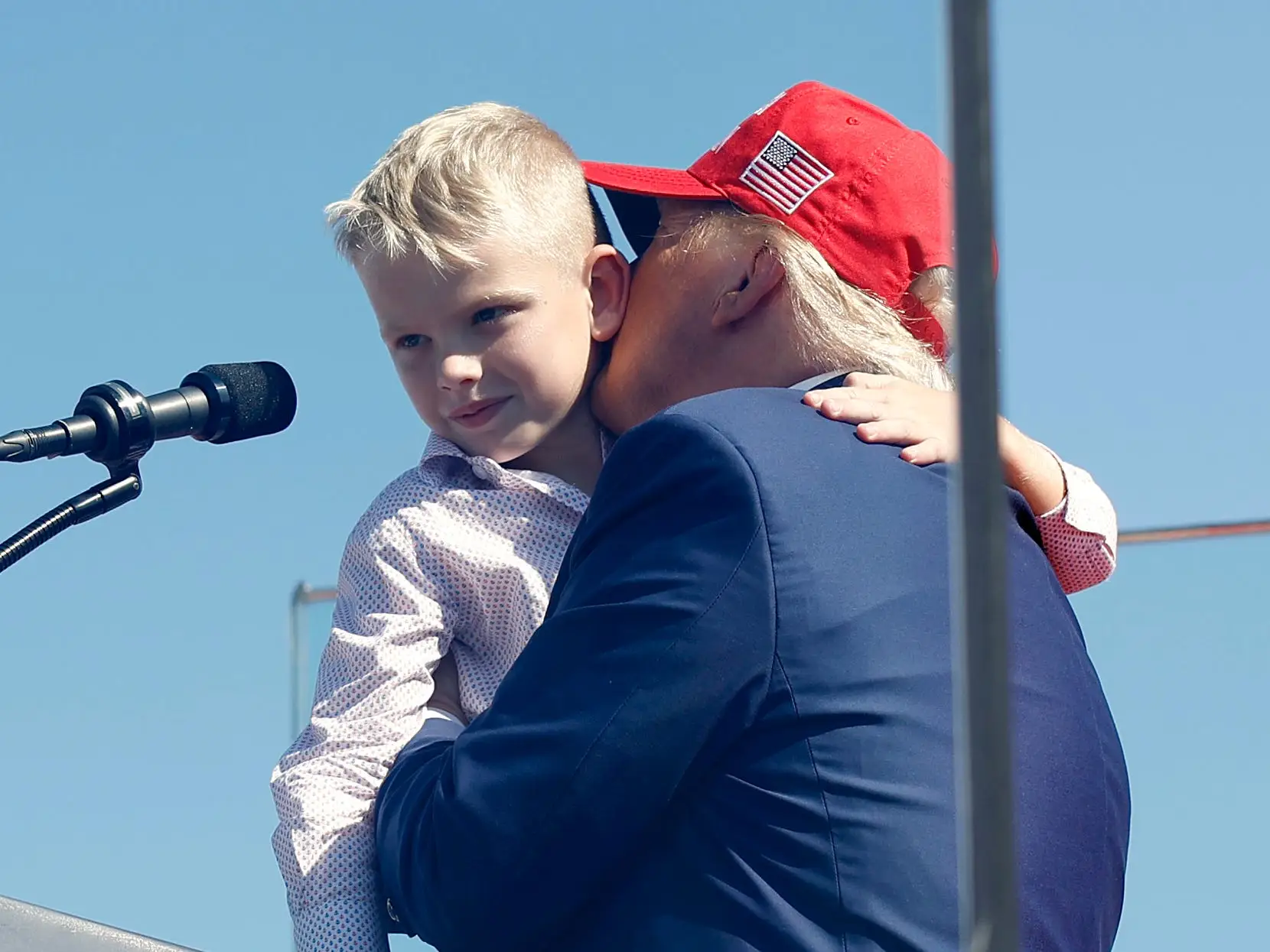 Donald Trump holding and kissing his grandson Luke onstage at a campaign rally.