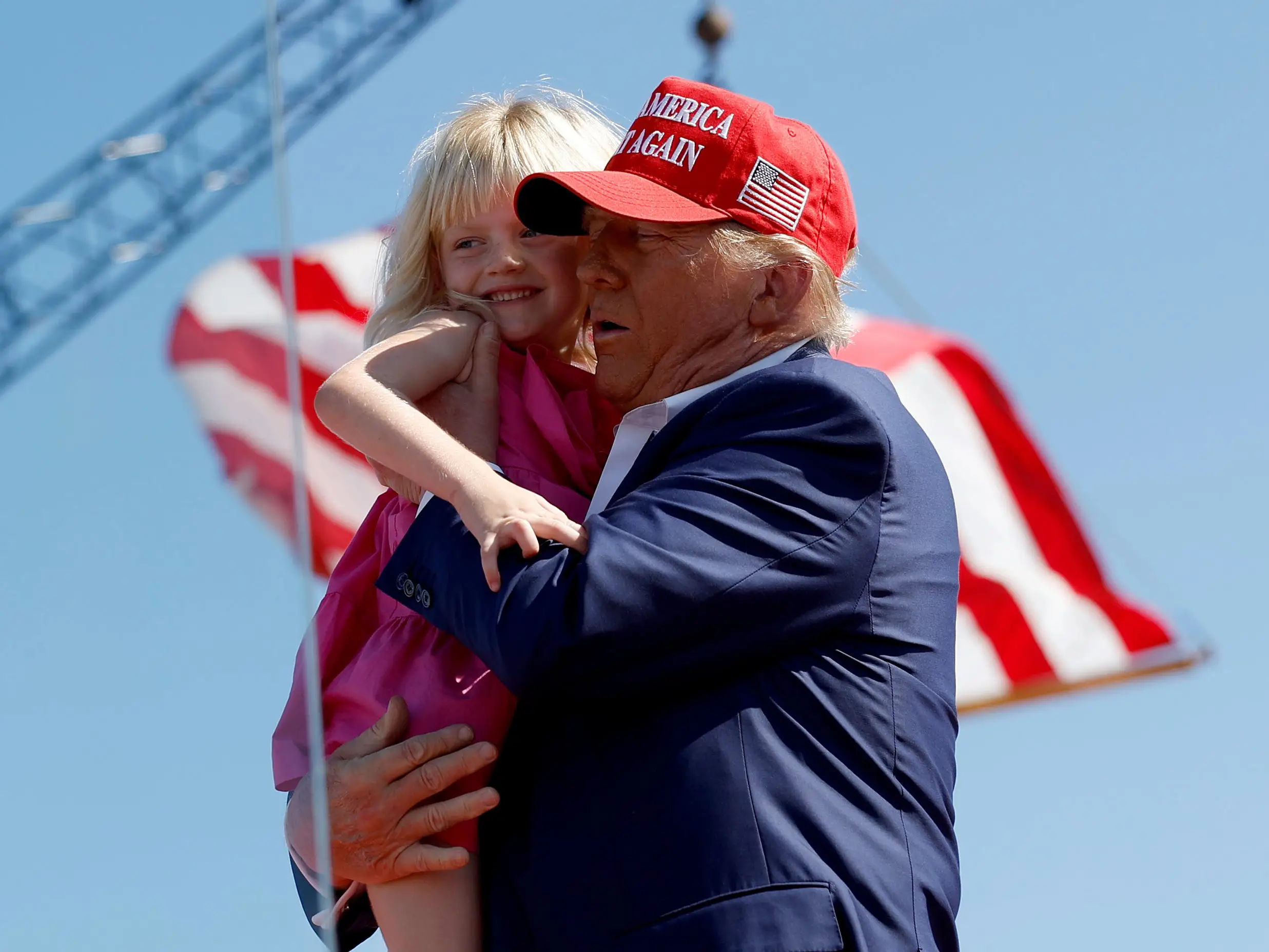 Donald Trump holding his granddaughter Carolina on stage at a campaign rally.
