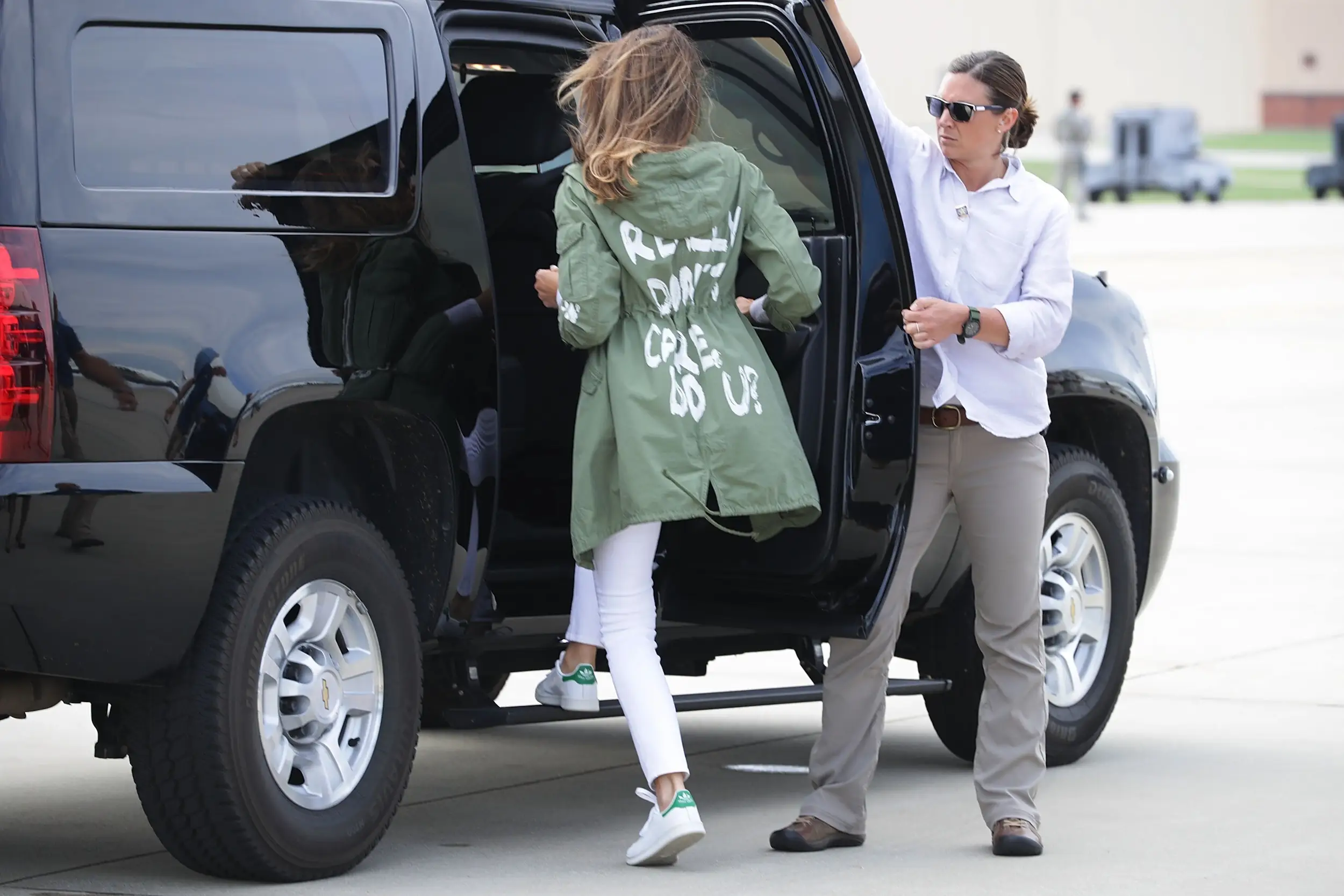 Melania Trump getting into a car while wearing a jacket that says 